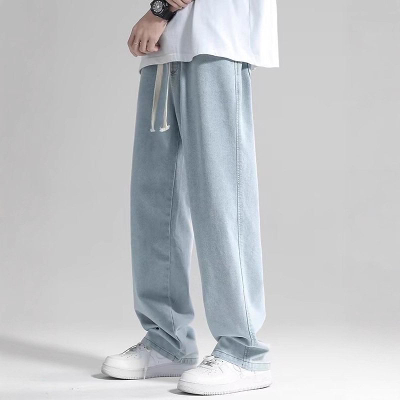Il tipo dei jeans dritti e' nuovo con la pelle estiva, con le gambe sciolte e i pantaloncini lunghi.